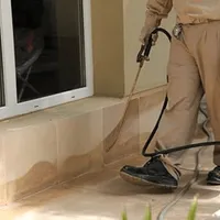General pest control technician spraying exterior perimeter around a home in Long Beach, CA