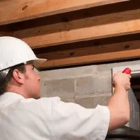 Termite inspection technician checking a basement wall and framing for termite activity in Long Beach, CA